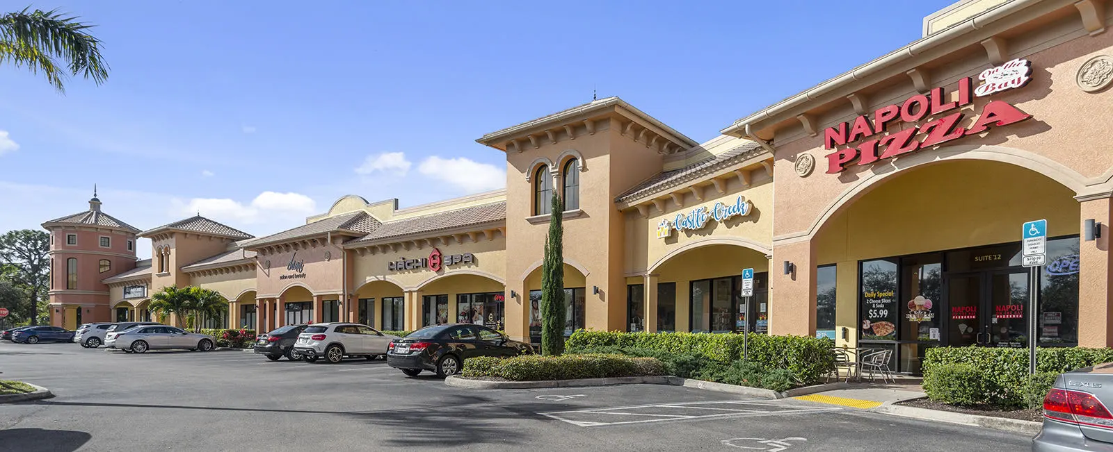 Exterior view of Sugden Park Plaza in Naples, Florida, featuring a neighborhood shopping center with multiple storefronts, landscaped grounds, parking areas, and convenient access for visitors.